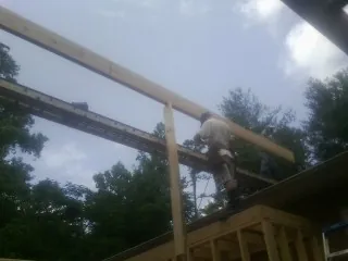 Carpenter setting a ridge beam over a new addition frame — Ice Dam Removal by Roofing Brothers in Boydton