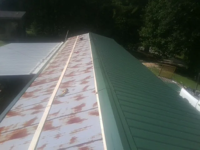 Old rusted panels beside newly installed green metal roofing — Wind Damage Roof Repair by Roofing Brothers in Boydton
