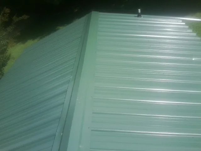 New green metal panels meeting at the ridge of a roof — Flat Roof Repair work by our crew in Boydton