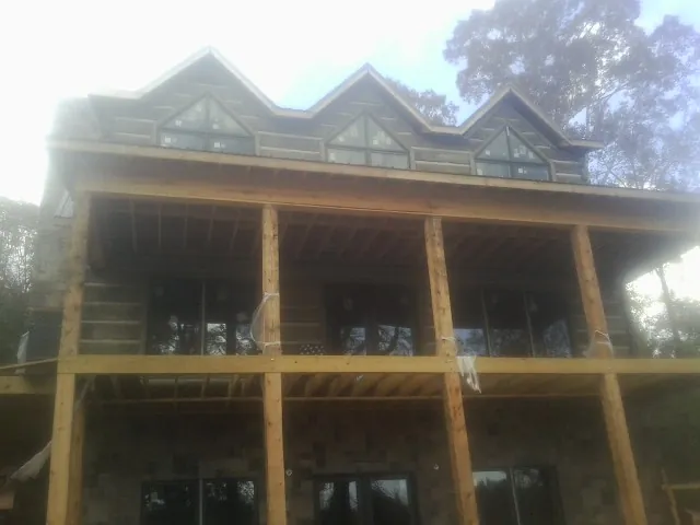 Dormers and porch framing on a large log home under construction — Roof Coating work by our crew in Boydton