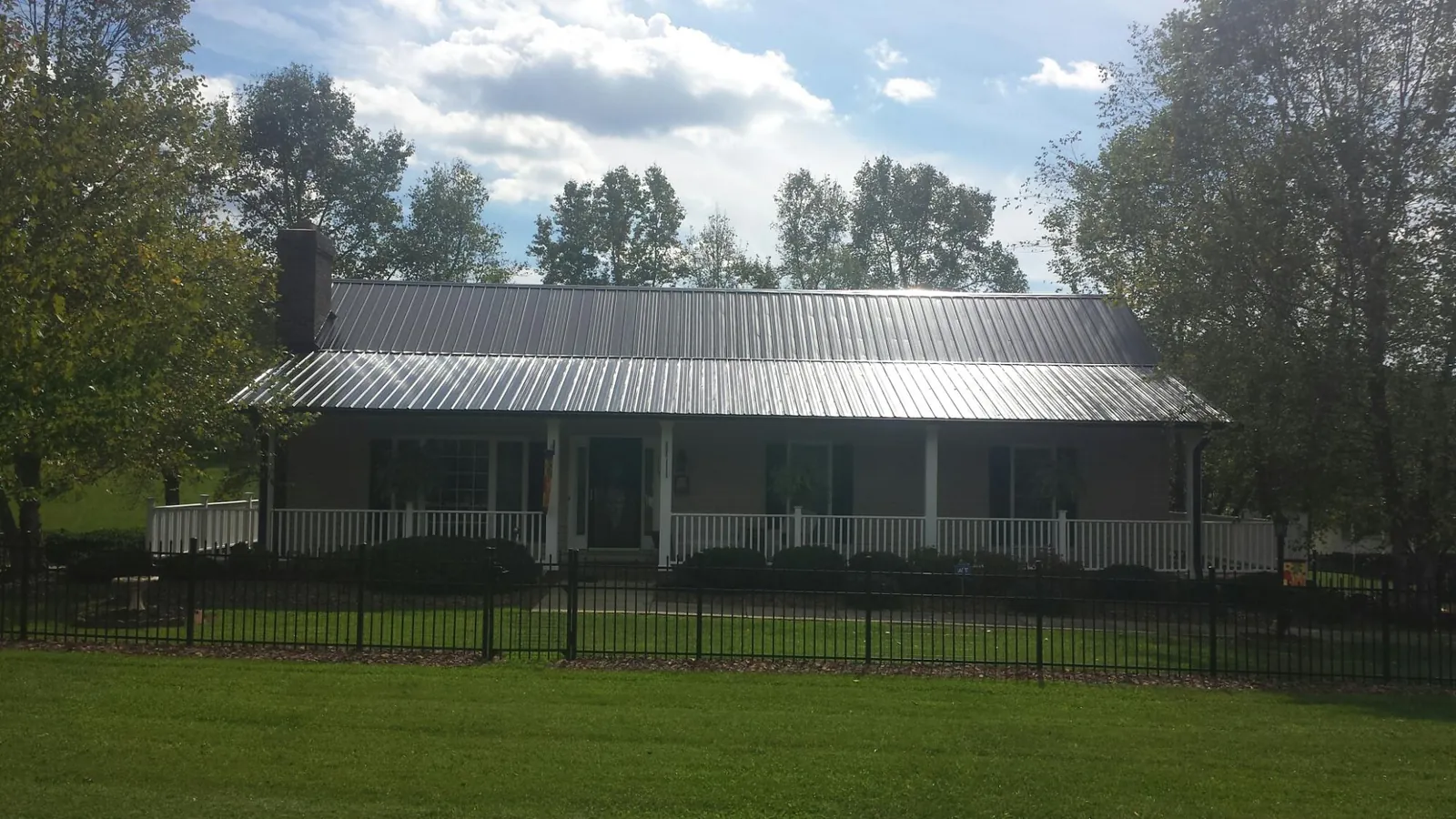 Gray metal roof on a brick ranch with a full width front porch — Gutter Guard Installation work by our crew in Boydton
