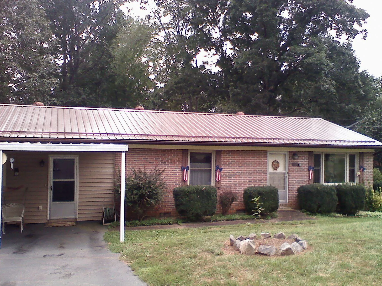 Bronze metal roof and carport on a brick ranch home — Roof Repair work by our crew in Boydton