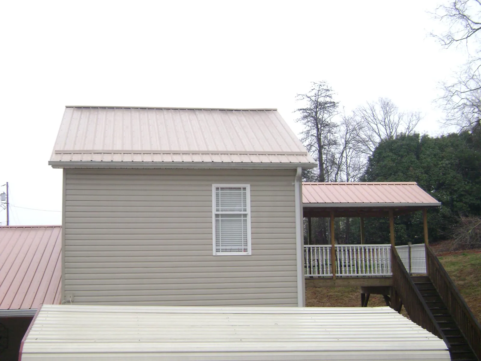Tan metal roofs on a two story addition and attached porch, from a Roof Replacement job in Boydton